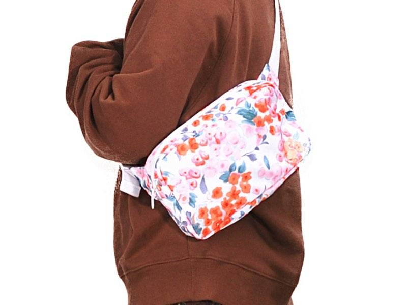 Side view of a girl dressed in brown carries a floral fanny pack.